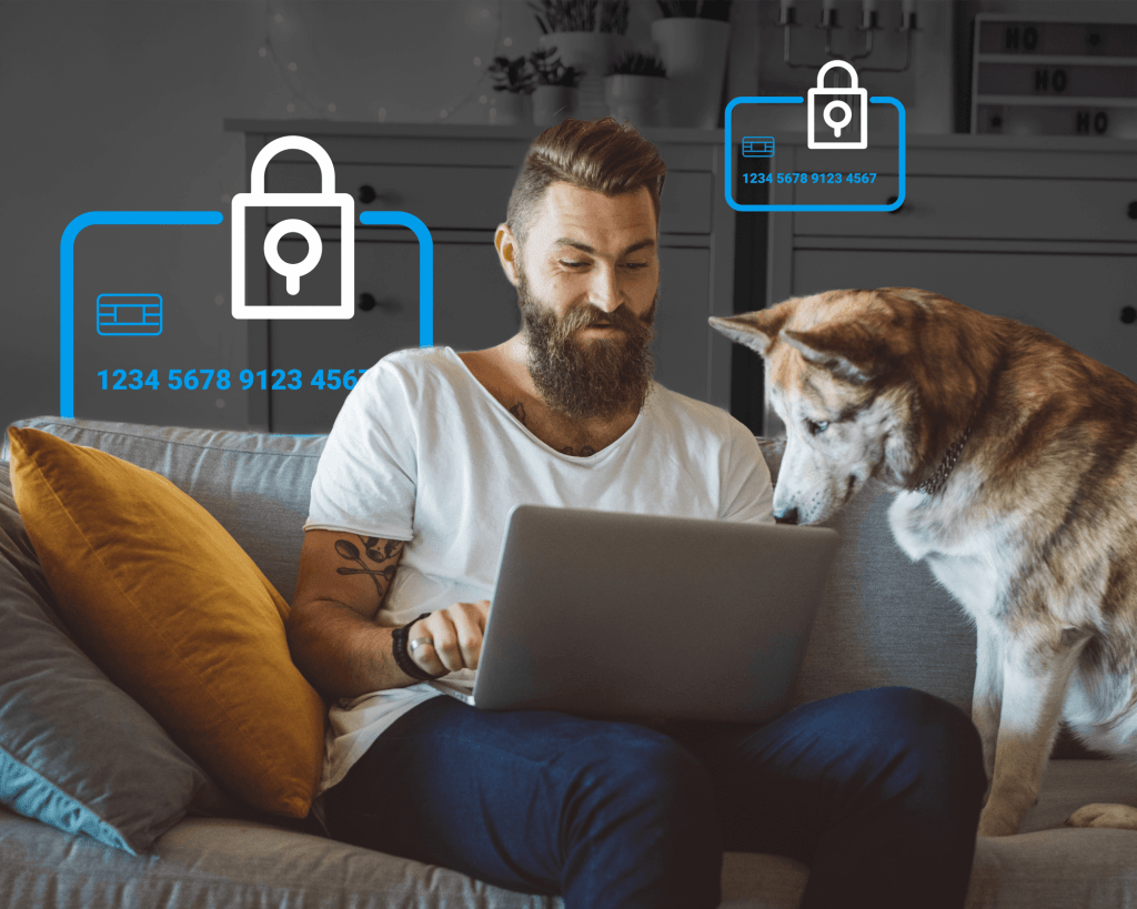 Young man sits on a couch looking at a computer while his dog watches on next to him. Icons of secure credit cards are in the background behind him.