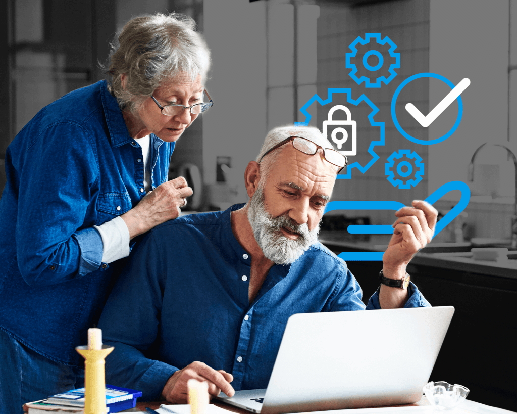 Older couple, one sits and one stands at a dining table looking at a laptop. Icons of gears and checkmarks to indicate identity recovery are in the background behind them.